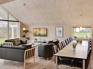 A modern living room with a sofa, chairs, a dining table, and a TV.