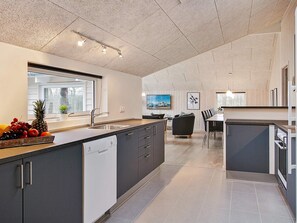 A modern kitchen with a central island, built-in appliances, and a dining area with a view of the outdoors.