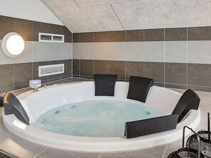 Une salle de bain moderne avec une baignoire sur pieds, un miroir rond et un radiateur fixé au mur.