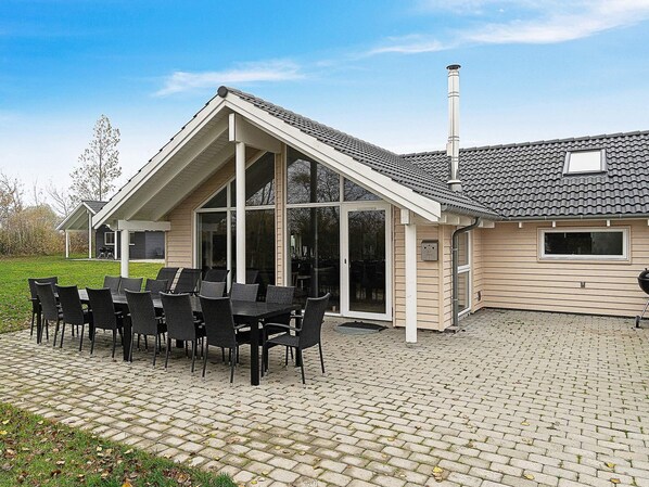 A house with a covered patio area featuring a dining table and chairs, a chimney, and a brick patio.