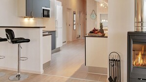 A modern kitchen with a central island, bar stools, a microwave, and a stove. - Holiday Home in Kappeln (Kappeln)