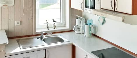 A compact kitchen with a sink, a microwave, a coffee maker, and a dishwasher.