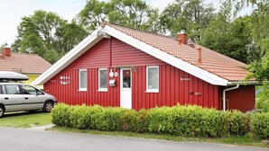 A red building with a white roof, a car parked in front, and a hedge in the foreground. - Holiday Home in Otterndorf (Otterndorf)