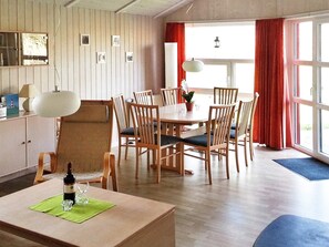 Un coin repas comprenant une table ronde et des chaises, un canapé, une lampe et une fenêtre avec des rideaux.