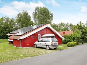 A red building with a car parked in front, surrounded by greenery. - Holiday Home in Otterndorf (Otterndorf)