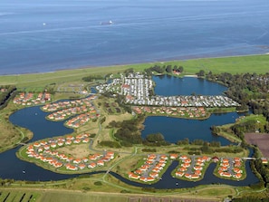 Vista aérea de uma área residencial à beira de um lago, com casas dispostas ao redor da água e ligadas por estradas.