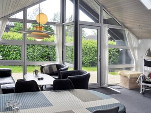 A modern room with large windows, a table with chairs, and a cozy seating area. - 4 Star Holiday Home in Struer (Struer)