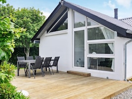 A modern house with a deck, large windows, and a chimney.