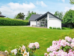 A modern house with a sloped roof, a covered patio, and a well-maintained lawn.