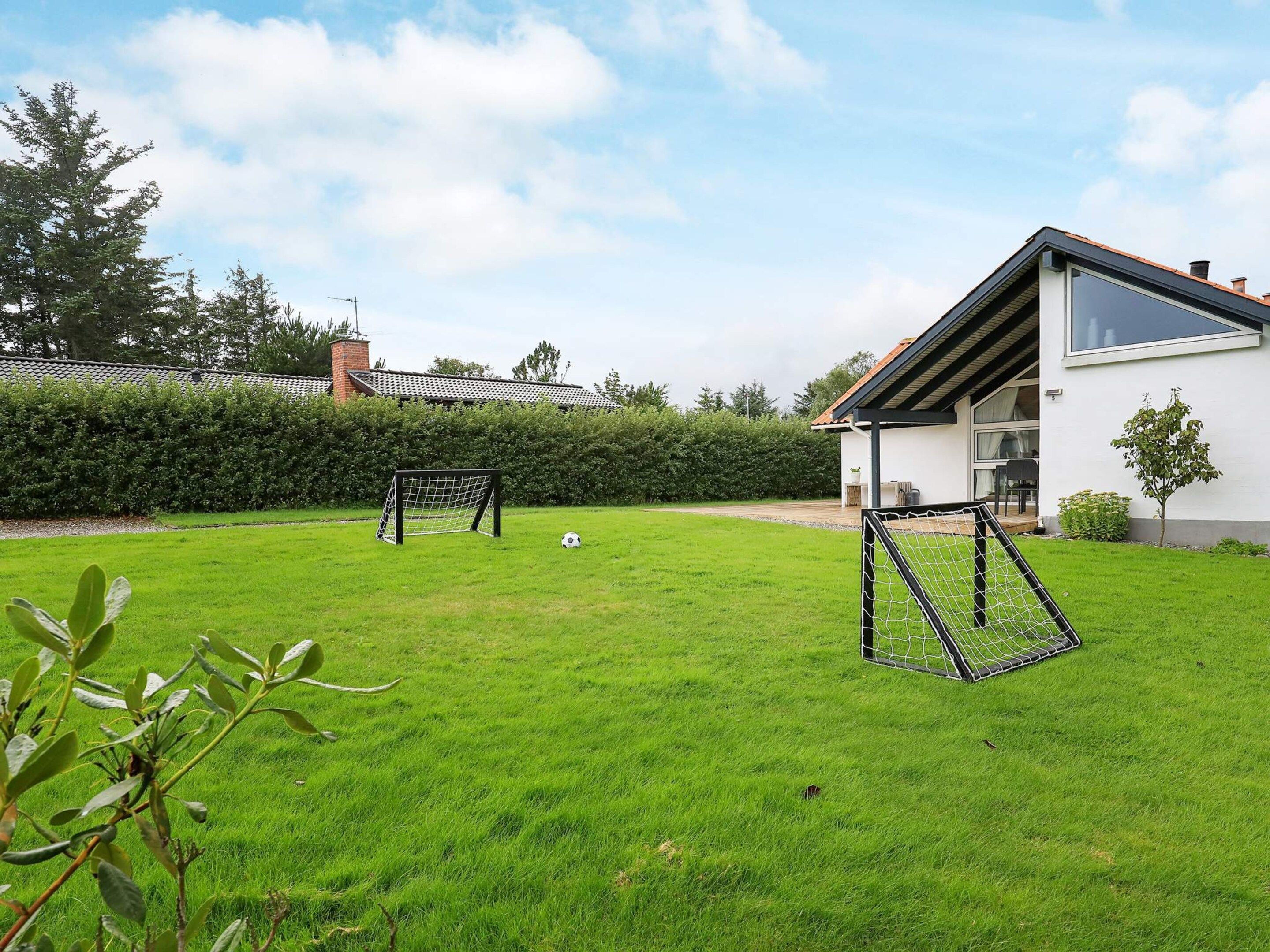 A residential property with a well-maintained lawn, a house with a sloped roof, and a visible chimney.