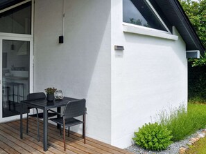 A modern house with a patio, a dining table with chairs, and a small garden area. - 4 Star Holiday Home in Struer (Struer)