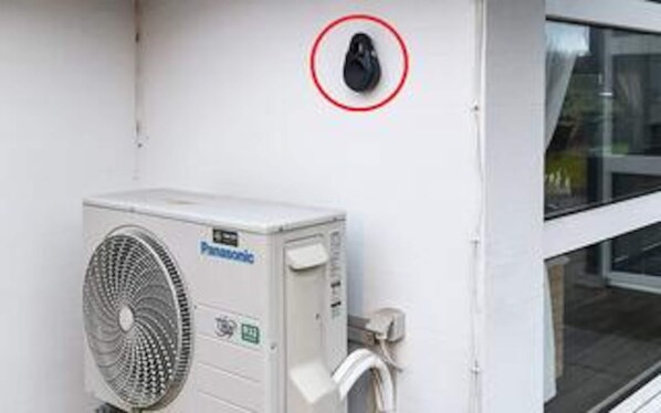 An air conditioning unit mounted on a white wall with a red circle highlighting a black object above it. - 4 Star Holiday Home in Struer (Struer)