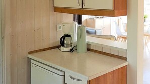 A compact kitchen with wooden cabinets, a coffee maker, and a kettle on the countertop. - Holiday Home in Otterndorf (Otterndorf)