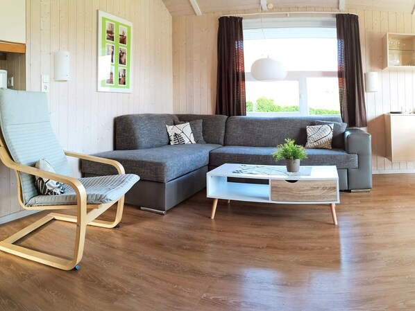 A modern living room with a sectional sofa, a wooden rocking chair, and a coffee table with a plant.
