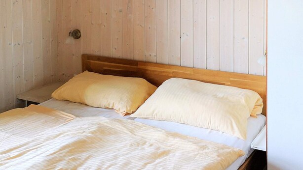 A single bed with a wooden headboard, two pillows, and a white mattress. - Holiday Home in Otterndorf (Otterndorf)