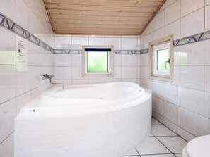 Une salle de bain avec une baignoire sur pieds, des murs carrelés et un plafond en bois.