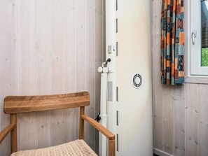 A wooden chair with a woven seat, a white radiator, and a window with patterned curtains.
