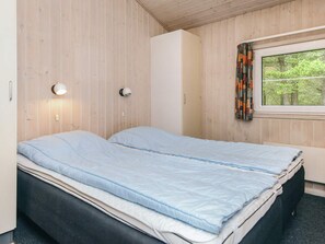 Une chambre avec deux lits, une armoire, une fenêtre avec des rideaux et des lampes fixées au mur.