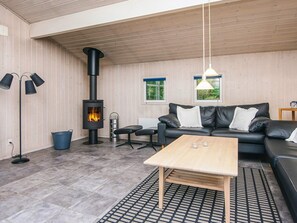 A modern living room with a black leather sofa, a wooden coffee table, a black floor lamp, and a wood-burning stove. - 5 Star Holiday Home in Henne (Henne)