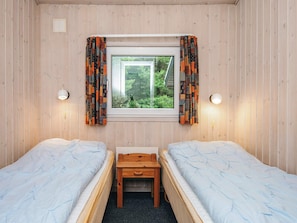 A room with two single beds, a small wooden table, a window with curtains, and two wall-mounted lamps. - 5 Star Holiday Home in Henne (Henne)