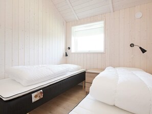 A room with two beds, a window, and a wall-mounted lamp. - 5 Star Holiday Home in Vaeggerlose (Vaeggerlose)