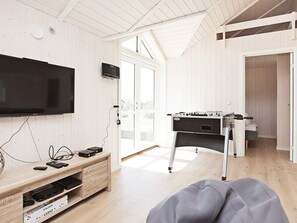 Quarto com televisão, mesa de pebolim e sofá.