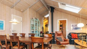 A cozy room with a wooden ceiling, a dining table with chairs, a sofa, and a cabinet with glass doors. - 6 Person Holiday Home in Humble (Sydlangeland)