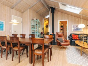 A cozy room with a wooden ceiling, a dining table with chairs, a sofa, and a cabinet with glass doors. - 6 Person Holiday Home in Humble (Sydlangeland)