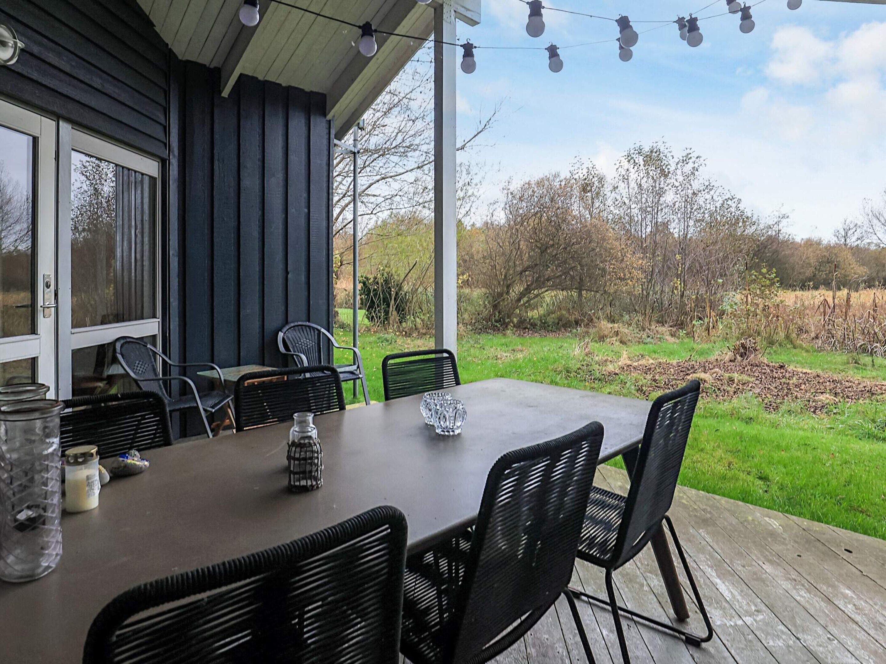 Un patio al aire libre con una mesa y sillas, un tarro de cristal y una vela sobre la mesa.