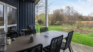 An outdoor patio with a table and chairs, a glass jar, and a candle on the table. - 6 Person Holiday Home in Humble (Sydlangeland)