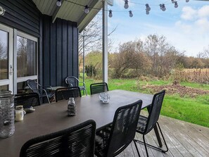 An outdoor patio with a table and chairs, a glass jar, and a candle on the table. - 6 Person Holiday Home in Humble (Sydlangeland)