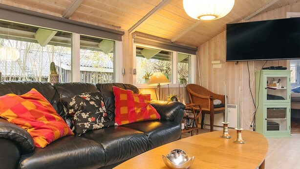 A living room with a leather sofa, a wooden coffee table, and a television mounted on the wall. - 6 Person Holiday Home in Humble (Sydlangeland)