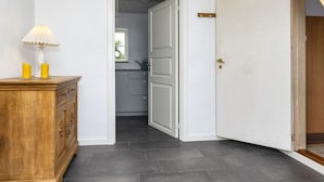 Un couloir avec une armoire en bois, une lampe et une porte donnant sur une cuisine.
