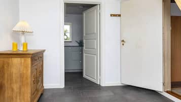 Um corredor com um armário de madeira, uma luminária e uma porta que dá para uma cozinha.