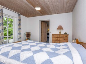 A bedroom with a large bed, wooden ceiling, a dresser, and a chair. - 6 Person Holiday Home in Thisted (Thisted)