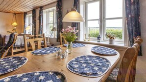 Un coin repas avec une table en bois, des sets de table bleus et des chaises.