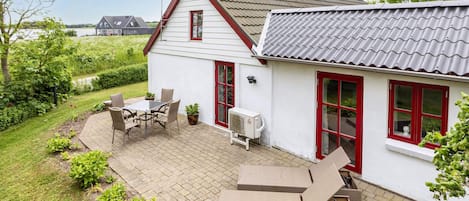 A house with a patio, outdoor furniture, and a view of the water.