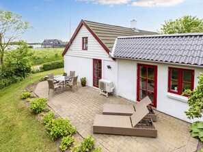 A house with a patio, outdoor furniture, and a view of the water.