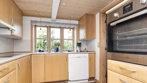Une cuisine avec des meubles en bois, un lave-vaisselle, une machine à café et un grand four.