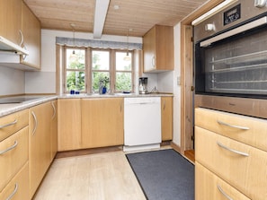 A kitchen with wooden cabinets, a dishwasher, a coffee maker, and a large oven.