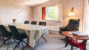 A conference room with a round table, chairs, a lamp, and a window with curtains.