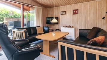 A modern living room with leather furniture, a wooden ceiling, and a television mounted on the wall.