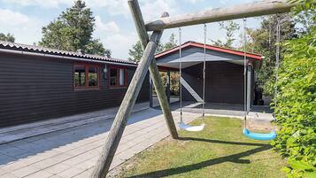 A wooden swing set in a backyard with a house in the background.
