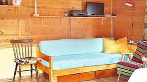 A cozy cabin interior with a wooden floor, a sofa with cushions, a small table, and a chair. - 4 Person Holiday Home in Vistdal (Molde)
