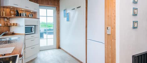 A kitchen with wooden cabinets, a microwave, and a large window.