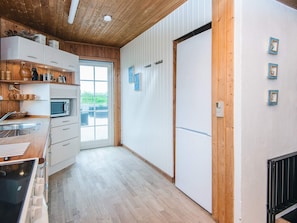Una cocina con armarios de madera, microondas y un ventanal amplio.