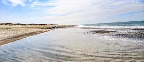 En strand med bred sandstrand og bløde bølger.