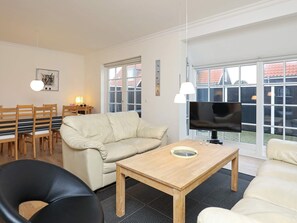 Una sala de estar con sofá, mesa de centro, televisor y un comedor con sillas y mesa.