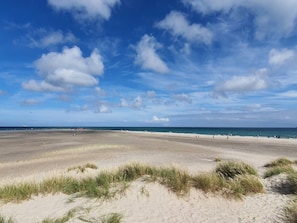 Una playa con dunas de arena y cielo despejado.