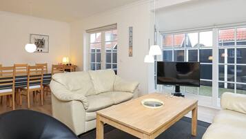 Una sala de estar moderna con un sofá, una mesa de centro, un televisor y un comedor con sillas y una mesa.